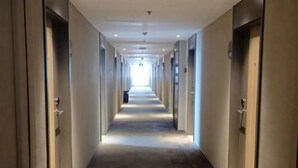 Passadís llarg i estret d'hotel, amb portes a banda i banda i un terra de moqueta.