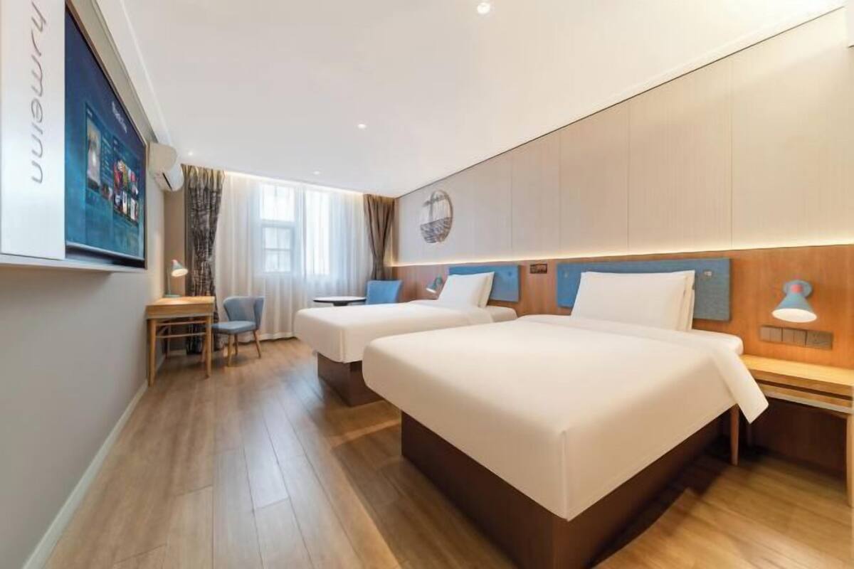 Une chambre d’hôtel avec deux lits, un bureau et une chaise.