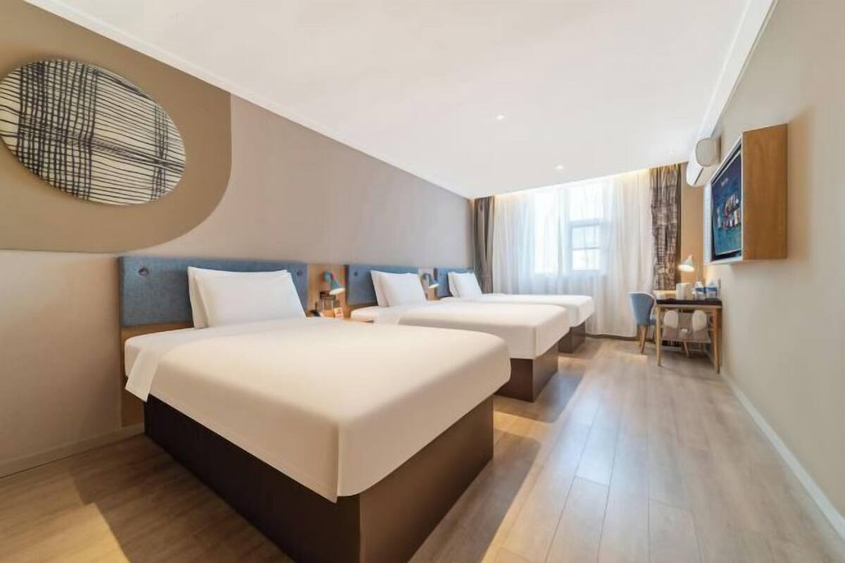 Une chambre d’hôtel avec deux lits, un bureau et une grande fenêtre.