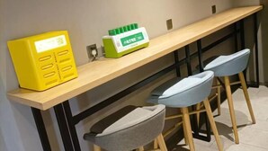 A modern kitchen with a wooden countertop, a yellow appliance, and a green appliance. There are two stools with grey cushions. - HomeInn·neo（Linyi Hedong District government store） (Linyi)