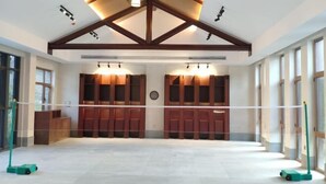 A spacious indoor area with a high ceiling, wooden beams, and a volleyball net.