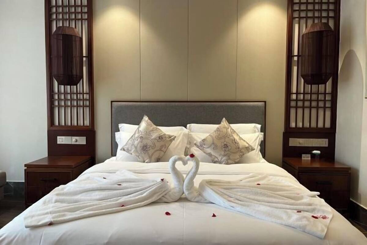 A hotel room with a bed, two nightstands, and a decorative wall panel.