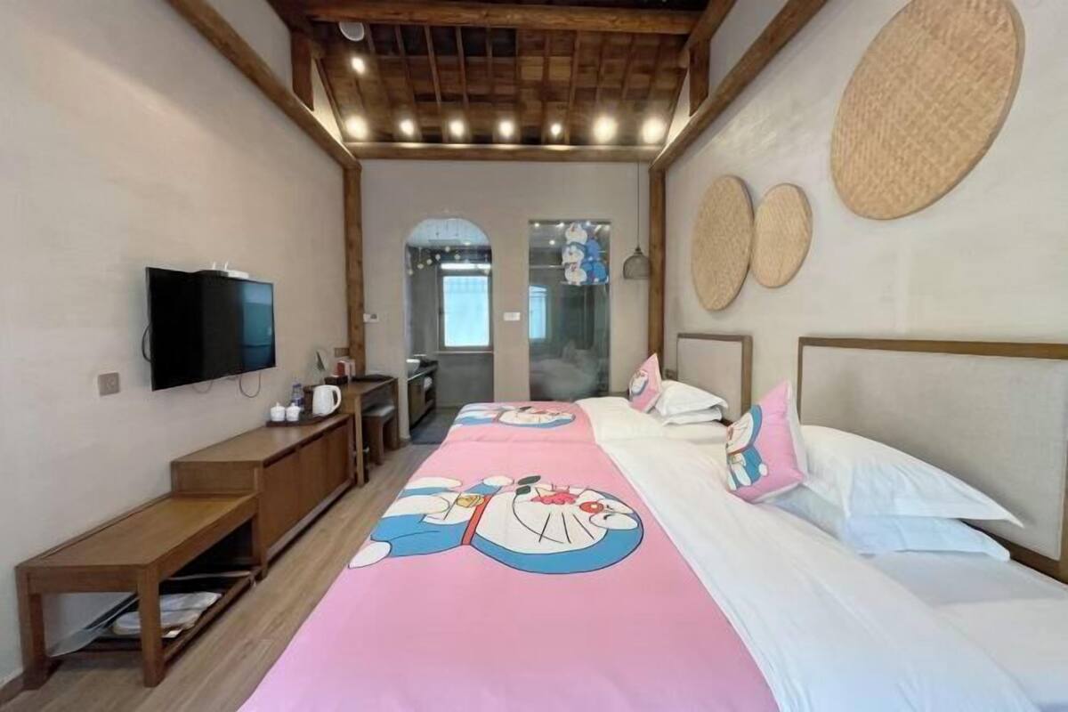 A bedroom with a bed, a TV, a wooden bench, and a breakfast bar.