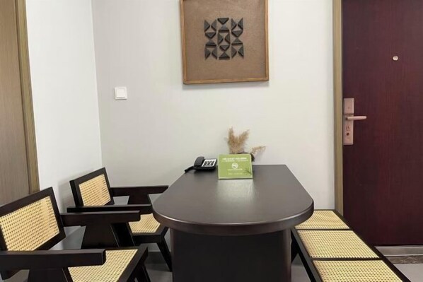 A conference room with a round table, black chairs with woven seats, a framed abstract artwork on the wall, a door, and a small plant on the table. - Shijiazhuang Pingshan Golden Benzhai Hotel (Pingshan)