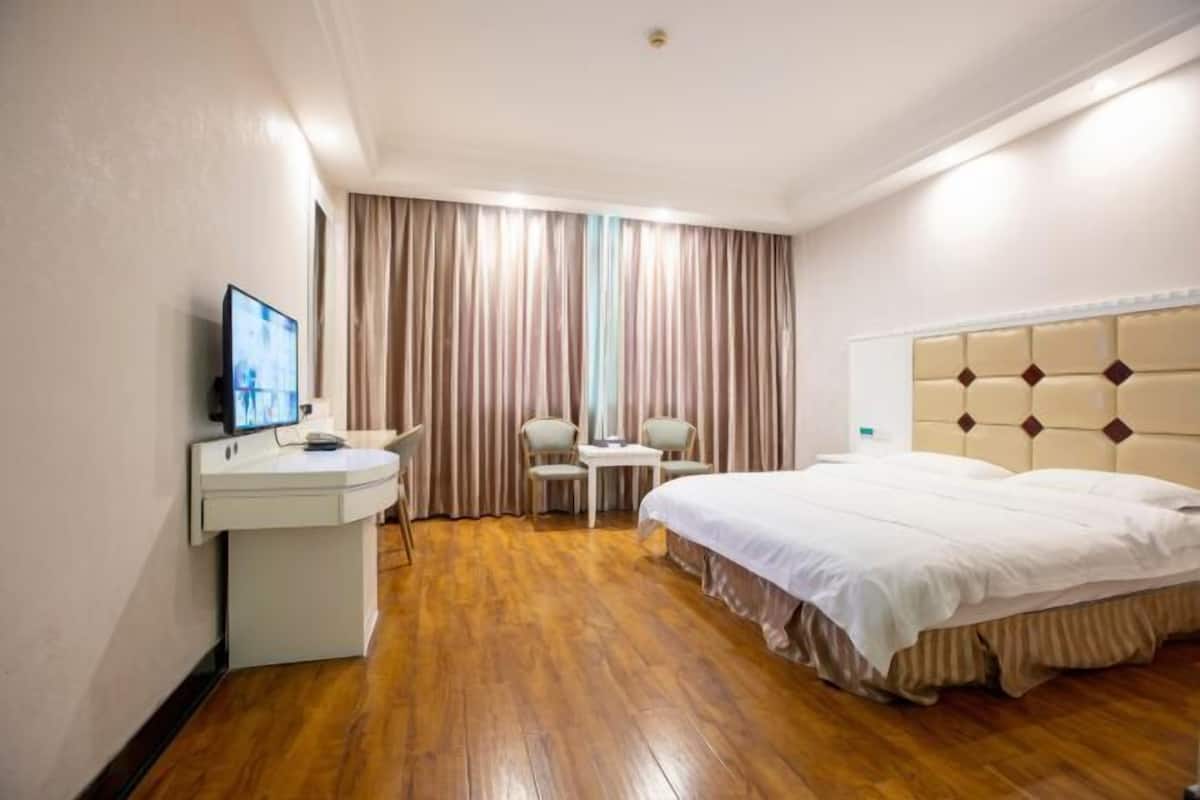 A hotel room with a bed, a desk with a computer, a chair, and a TV.