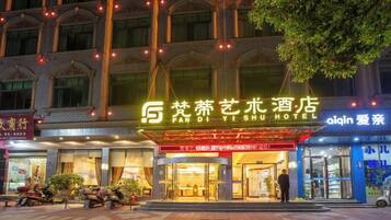 A hotel with a prominent sign, a covered entrance, and a person standing at the entrance.