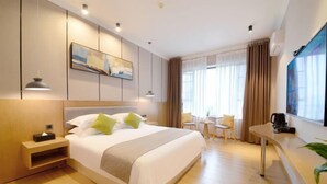 Una habitación de hotel moderna con una cama grande, mesitas de noche, un escritorio y vistas al exterior.