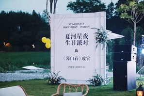A banner with text for a birthday party, a stage with speakers, and a chair in a grassy outdoor setting. - Taishun Zhuli Yunxi Homestay (Taishun)