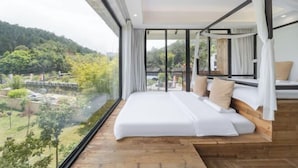 A bedroom with a large bed, a view of greenery, and a balcony. - Taishun Zhuli Yunxi Homestay (Taishun)