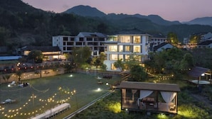 A modern hotel with multiple floors, a well-lit outdoor area, and a view of surrounding hills. - Taishun Zhuli Yunxi Homestay (Taishun)