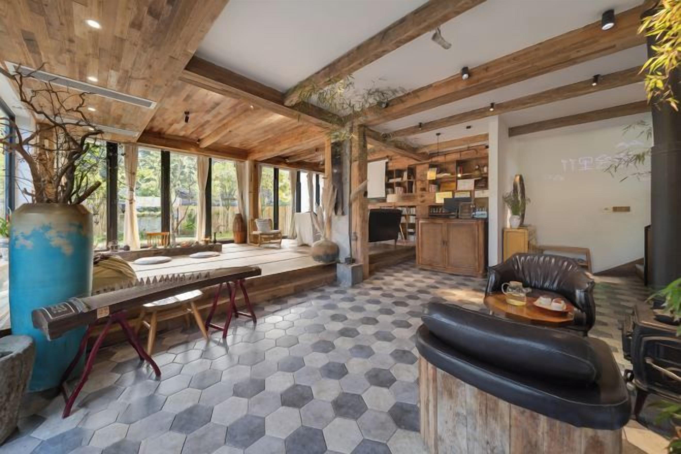 Un amplio salón con techo de madera, suelo de baldosas hexagonales y una zona de estar con sofá y mesa de comedor.