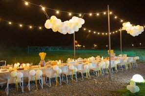 Un espacio exterior con mesas, sillas, luces de cadena y globos.