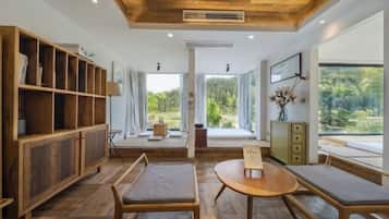 A modern interior with wooden flooring, a round table, benches, and a built-in bookshelf.