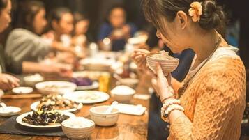 A person seated at a wooden table with various dishes, suggesting a communal dining setting.