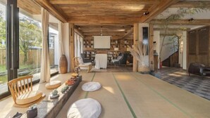 A spacious room with a wooden ceiling, tatami mats, a sofa, and a view of the outdoors. - Taishun Zhuli Yunxi Homestay (Taishun)