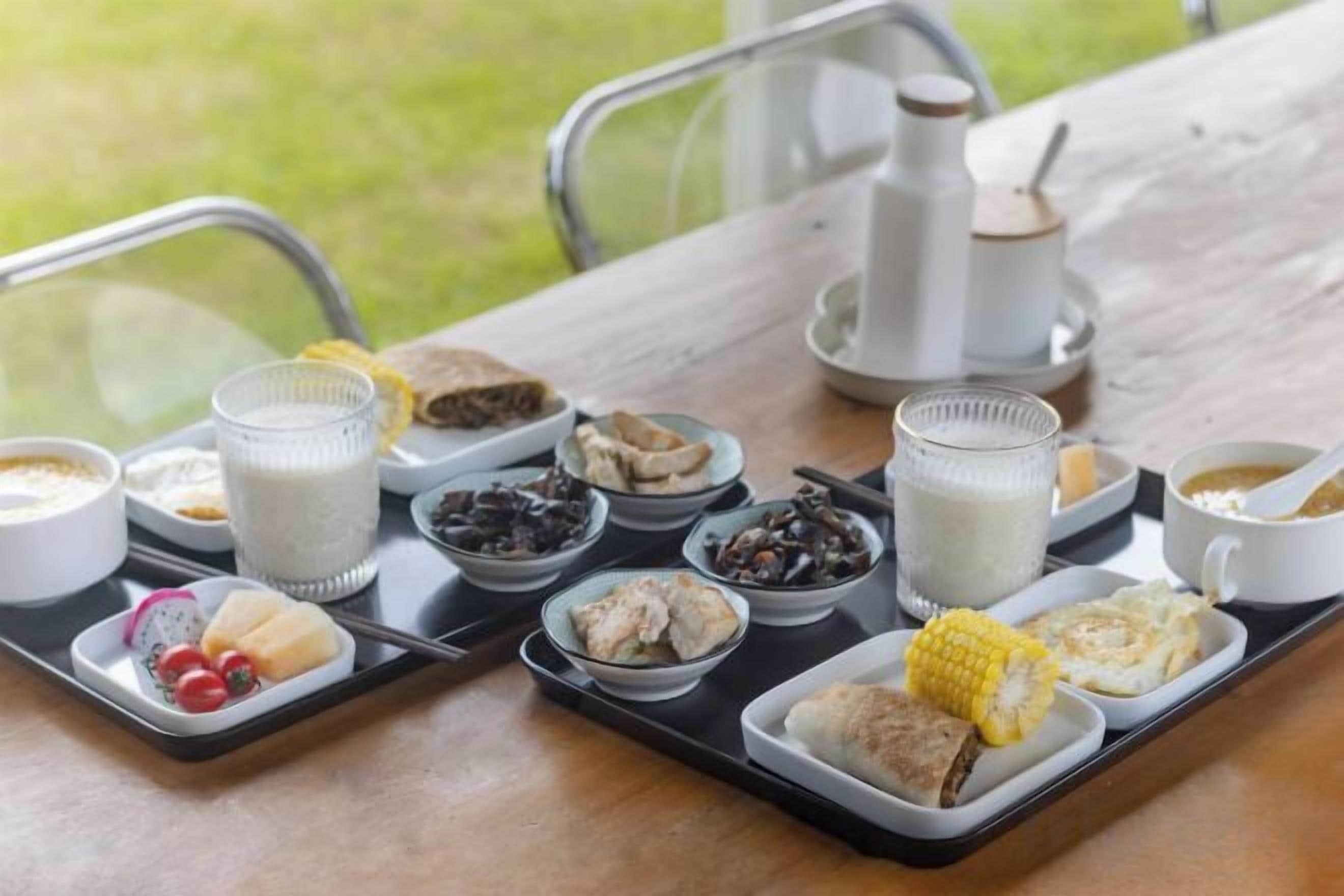 A meal tray with various food items and a coffee pot on a wooden table.