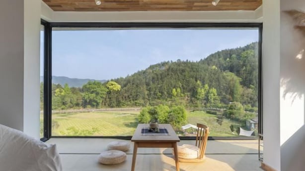 A room with a large window, a wooden table with a plant, and a chair. - Taishun Zhuli Yunxi Homestay (Taishun)