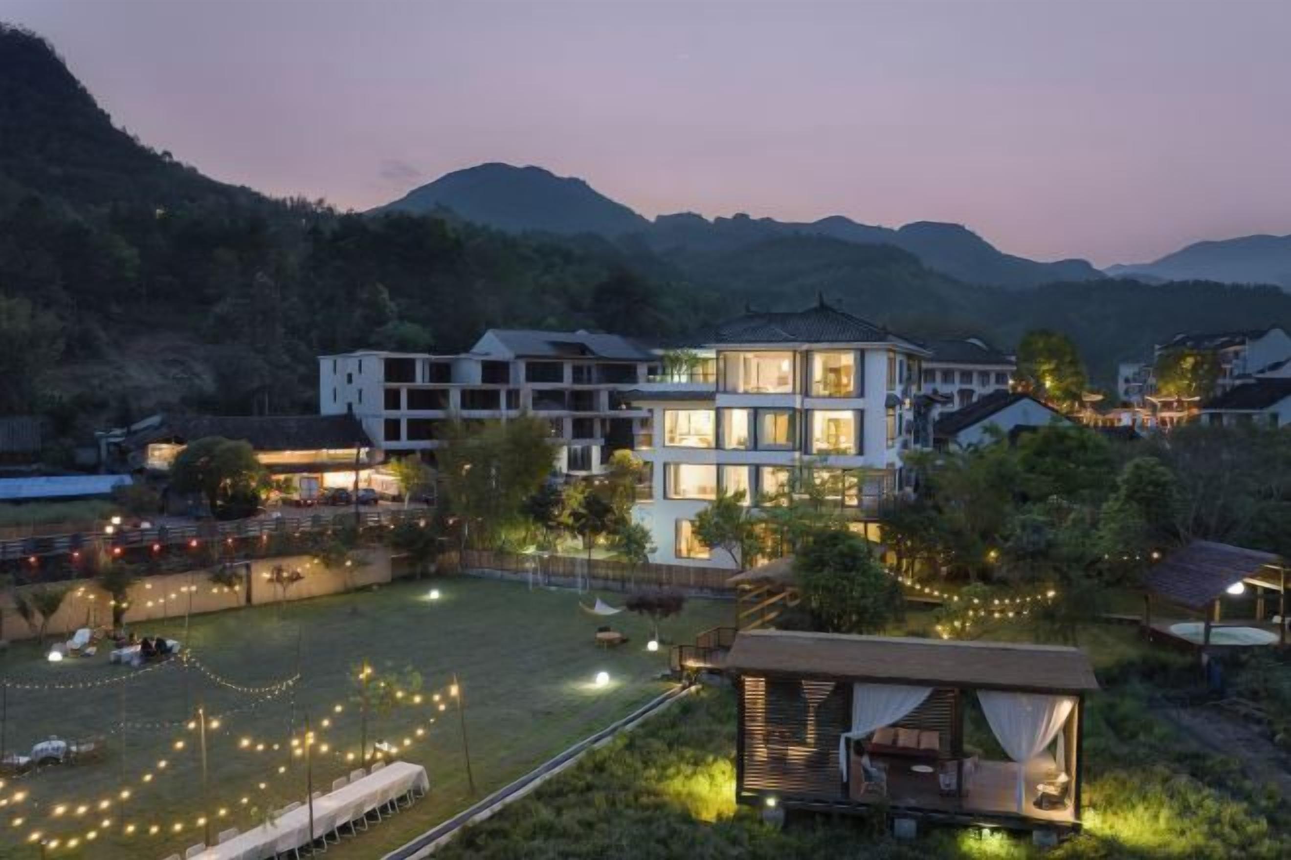 Un hôtel à plusieurs étages doté d’une cour bien éclairée, entourée de montagnes.