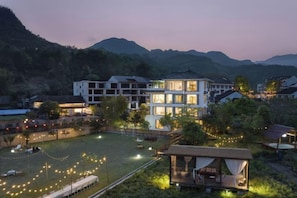 Un hotel de varios pisos con un patio luminoso, rodeado de montañas.