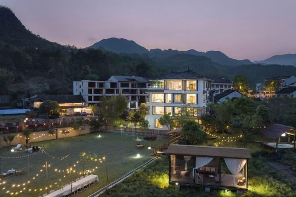 A multi-story hotel with a well-lit courtyard, surrounded by mountains. - Taishun Zhuli Yunxi Homestay (Taishun)