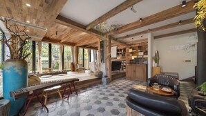 A spacious living area with a wooden ceiling, hexagonal patterned floor, and a large window providing natural light. - Taishun Zhuli Yunxi Homestay (Taishun)