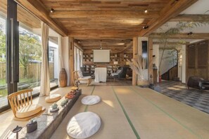 Een traditionele Japanse kamer met tatami vloeren, een laag houten plafond en uitzicht op de natuur.