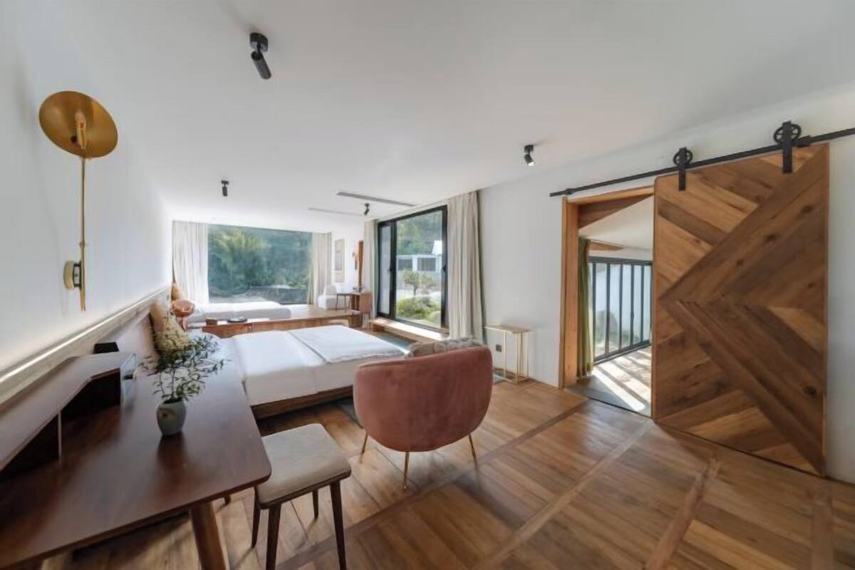 Een moderne slaapkamer met een groot bed, een houten vloer en een schuifdeur naar een balkon.