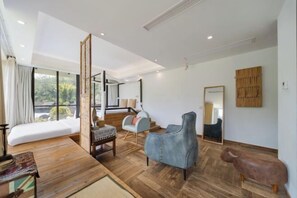 A modern living room with a wooden floor, a sofa, a blue armchair, and a small wooden table.