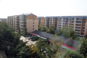 A multi-story residential building with balconies, surrounded by trees and a red-roofed structure. - Shankee Hotel (Tancheng Sifang Furniture Plaza) (Tancheng)