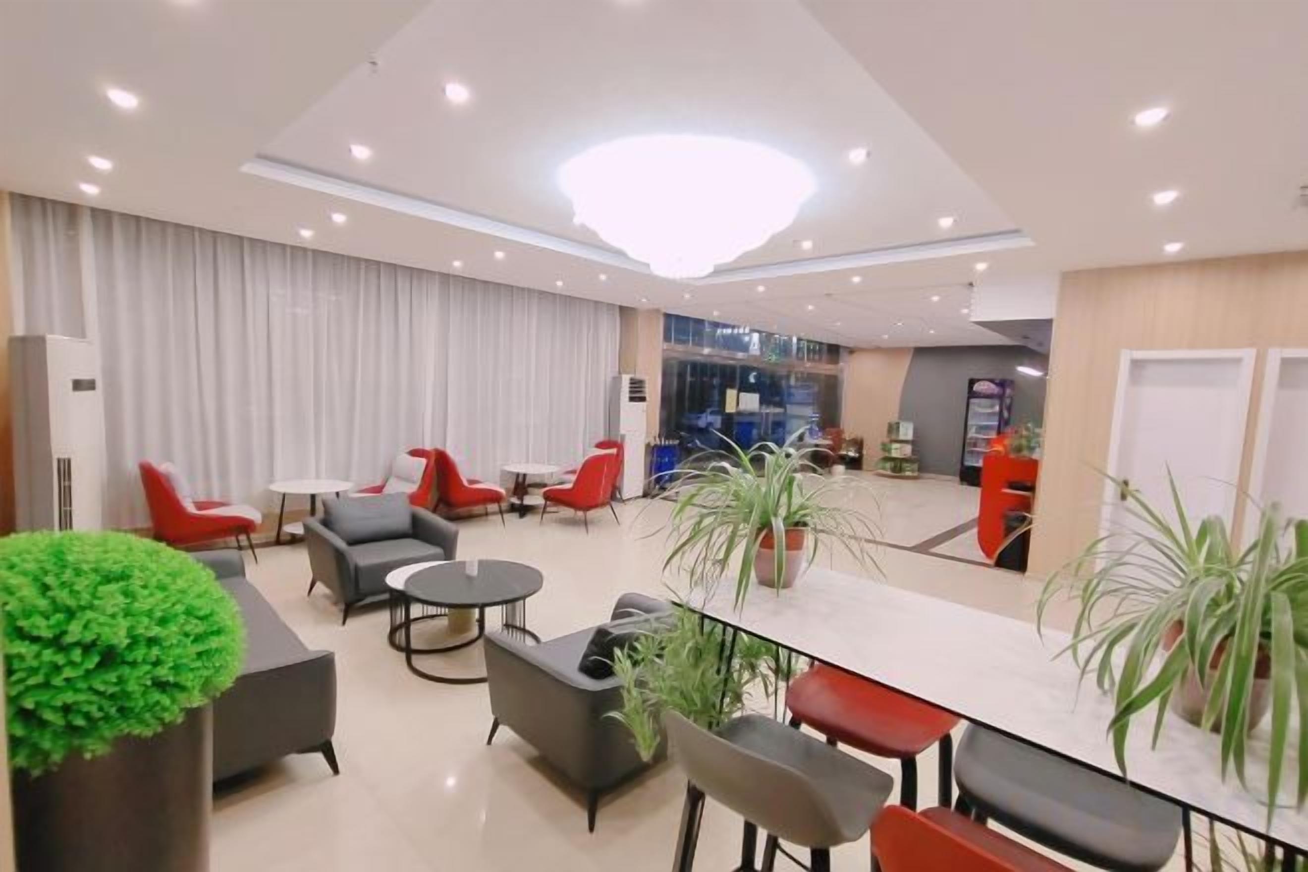 A modern hotel lobby with seating areas, a reception desk, and a large window.