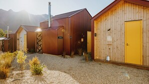 A row of rustic buildings with metal roofs and wooden walls, set against a mountainous backdrop. - The Great Glenorchy Alpine Base Camp (Glenorchy)