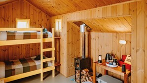 A wooden cabin with bunk beds, a wood stove, and a small table with a kettle and cups. - The Great Glenorchy Alpine Base Camp (Glenorchy)