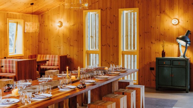 A wooden cabin with a long dining table set for a meal, wooden walls, and a green cabinet. - The Great Glenorchy Alpine Base Camp (Glenorchy)