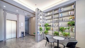 A modern interior with a marble floor, a glass partition with shelves, and two chairs around a small table. - Home Inn Subayun (Rugao)