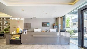 A modern reception area with a counter, a digital screen, and a seating area. - Home Inn Subayun (Rugao)