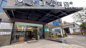 The exterior of a hotel with a modern facade, a covered entrance, and signage indicating it is a hotel.