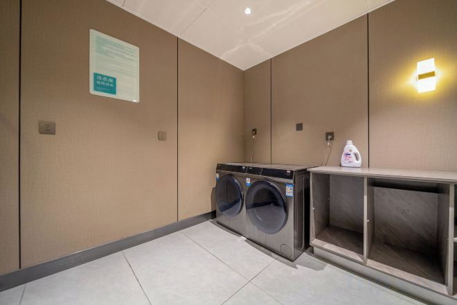A hotel room with a washing machine, a cabinet, and a wall-mounted light fixture.