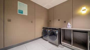 A hotel room with a washing machine, a cabinet, and a wall-mounted light fixture.