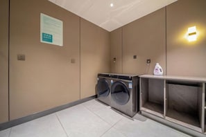 A hotel room with a washing machine, a cabinet, and a wall-mounted light fixture. - Home Inn Subayun (Rugao)