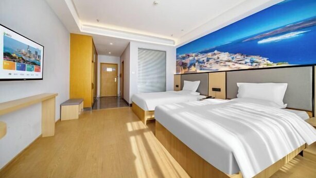 A modern hotel room with a large bed, a television, and a cityscape mural on the wall. - Home Inn Subayun (Rugao)