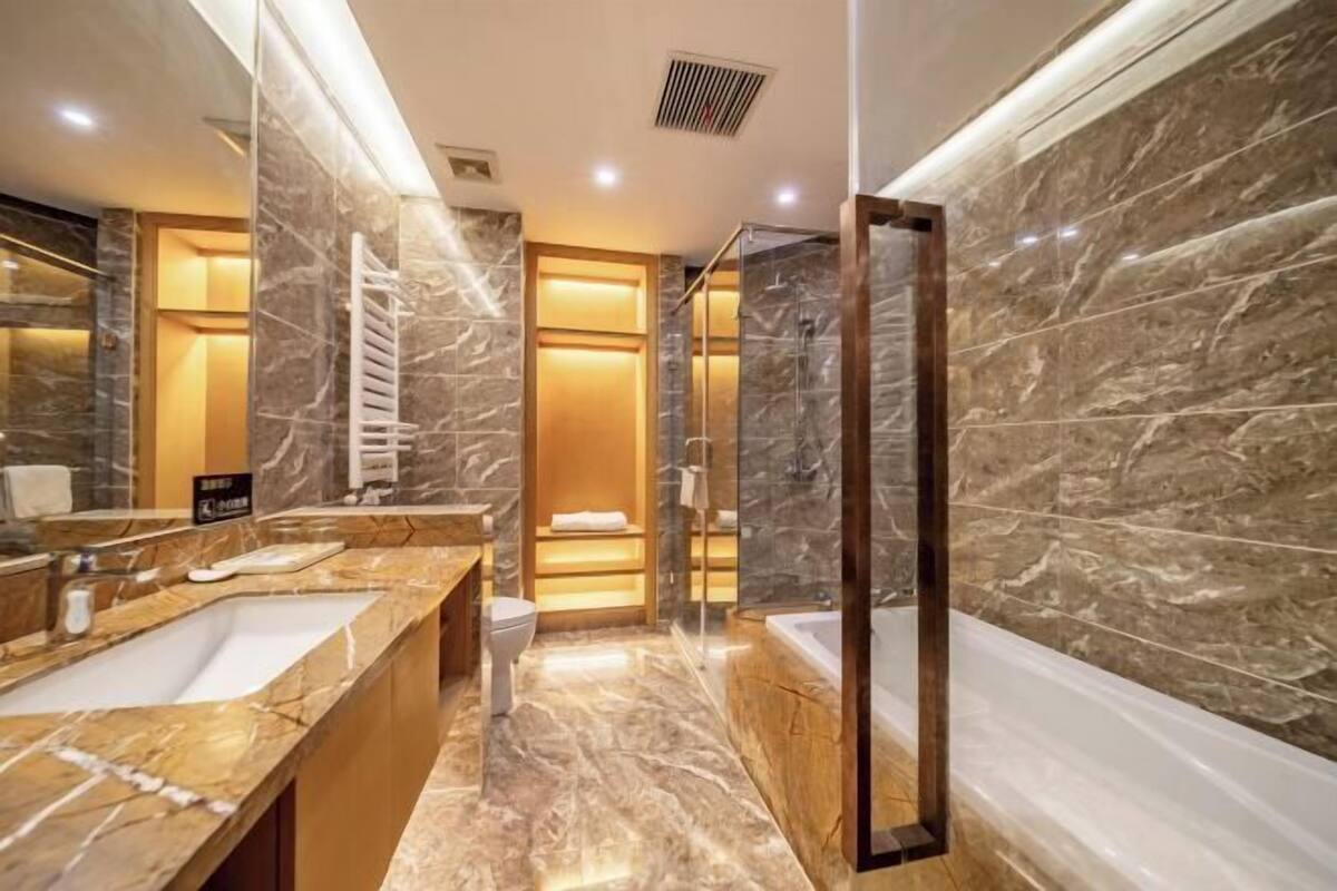 A modern bathroom with marble countertops, a bathtub, and a glass-enclosed shower.