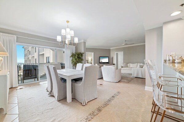 A modern living room with a dining area, a large window, and a view of a building. - BEACHFRONT RESORT, FAMILY FRIENDLY, TOP AMENITIES (Orange Beach)