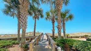 A wooden boardwalk leading to a beach, surrounded by palm trees and greenery. - BEACHFRONT RESORT, FAMILY FRIENDLY, TOP AMENITIES (Orange Beach)