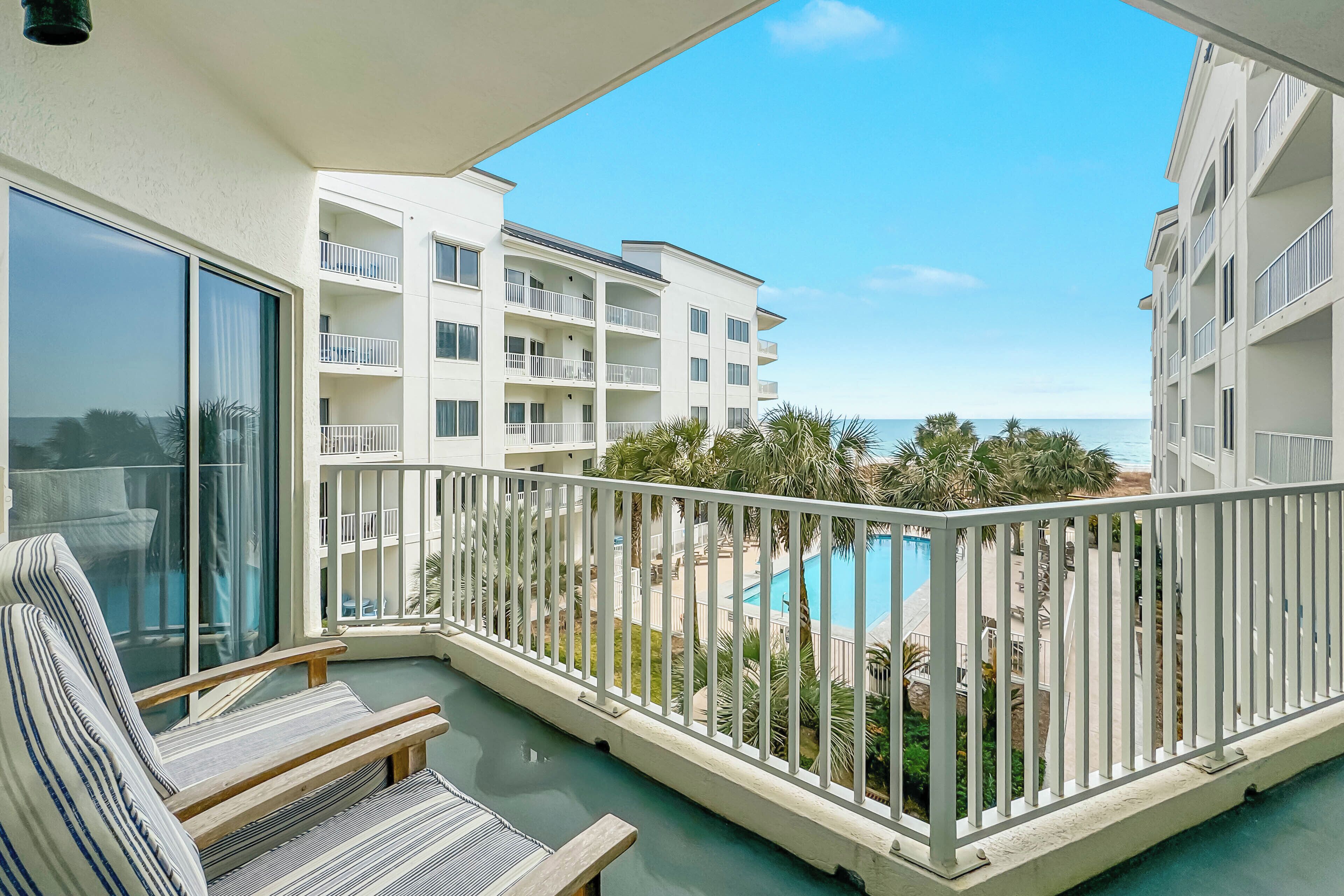 Un balcon donnant sur une piscine et un immeuble doté de nombreux balcons.