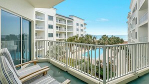 A balcony with a view of a pool and a building with multiple balconies. - BEACHFRONT RESORT, FAMILY FRIENDLY, TOP AMENITIES (Orange Beach)