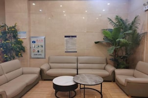 Un vestíbulo con sofás color crema, una mesa redonda y un cartel en la pared.
