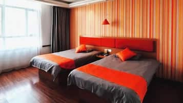 A hotel room with two beds, wooden flooring, a striped wall, and a red pendant light.