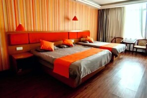 Une chambre d’hôtel avec deux lits, un plancher en bois, un mur à rayures et une fenêtre avec des rideaux.