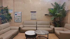 Un área de recepción con un sofá beige, una mesita redonda y una planta en maceta.