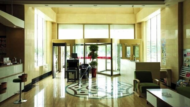 Un hall espacioso con piso pulido, una recepción, zona de estar y grandes ventanales que dejan entrar luz natural.